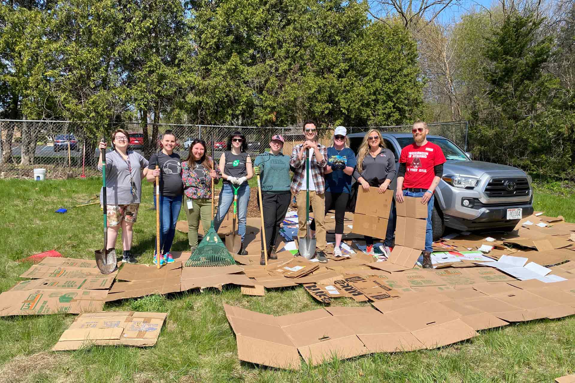 A group of UW Credit Union employees hold gardening tools.