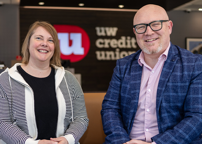 Sunny and Sam McDaniel, UW Credit Union members, sit together and smile brightly in a UW Credit Union branch location.