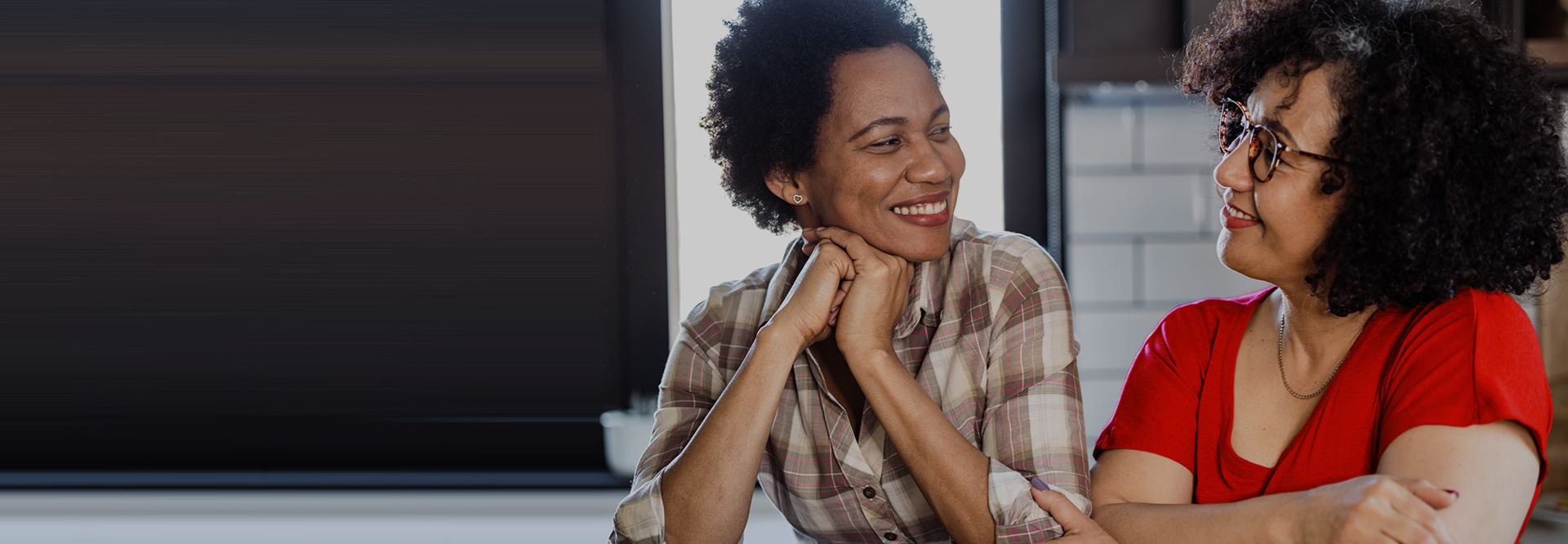 Two middle aged women look at each other and smile.