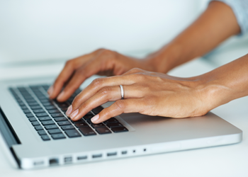 A closeup of hands typing on a laptop.