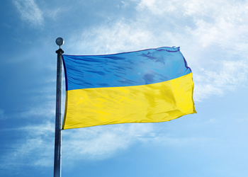 The Ukrainian flag flies against a bright blue sky.